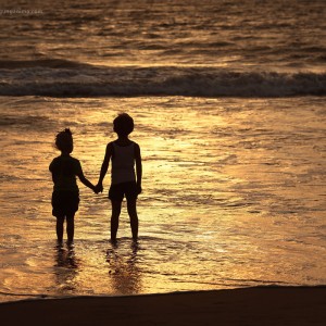 Мальчик и девочка у моря держатся за руки на закате. Фото Люся Маратканова.