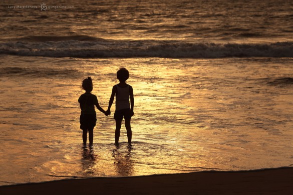 Мальчик и девочка у моря держатся за руки на закате. Фото Люся Маратканова.