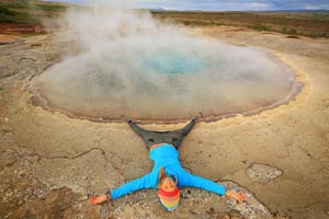 человек лежит у гейзера в Исландии. Фото Люси Мараткановой