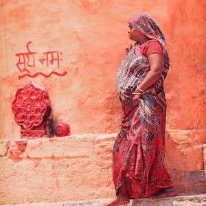 женщина в красном на фоне красных стен в варанаси в индии
