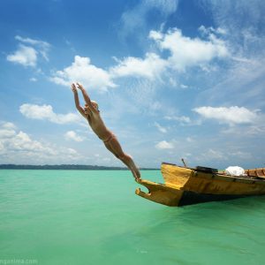 girl is jumping in the turquiose sea from boat in havelock island in andaman in india