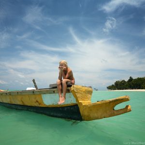 девочка сидит на лодке в море у берега острова хэвелок в андаманских островах в индии