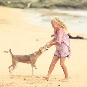 Девочка играет с собакой на берегу острова Нил в Андаманских островах в Индии